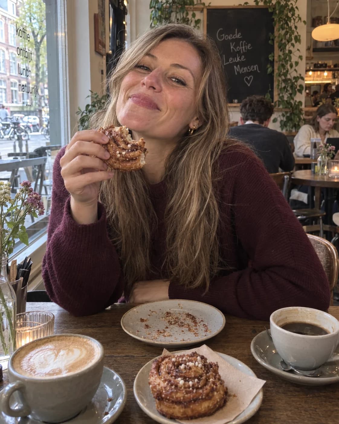 Sophie met koffie en een kaneelbroodje aan een cafétafel