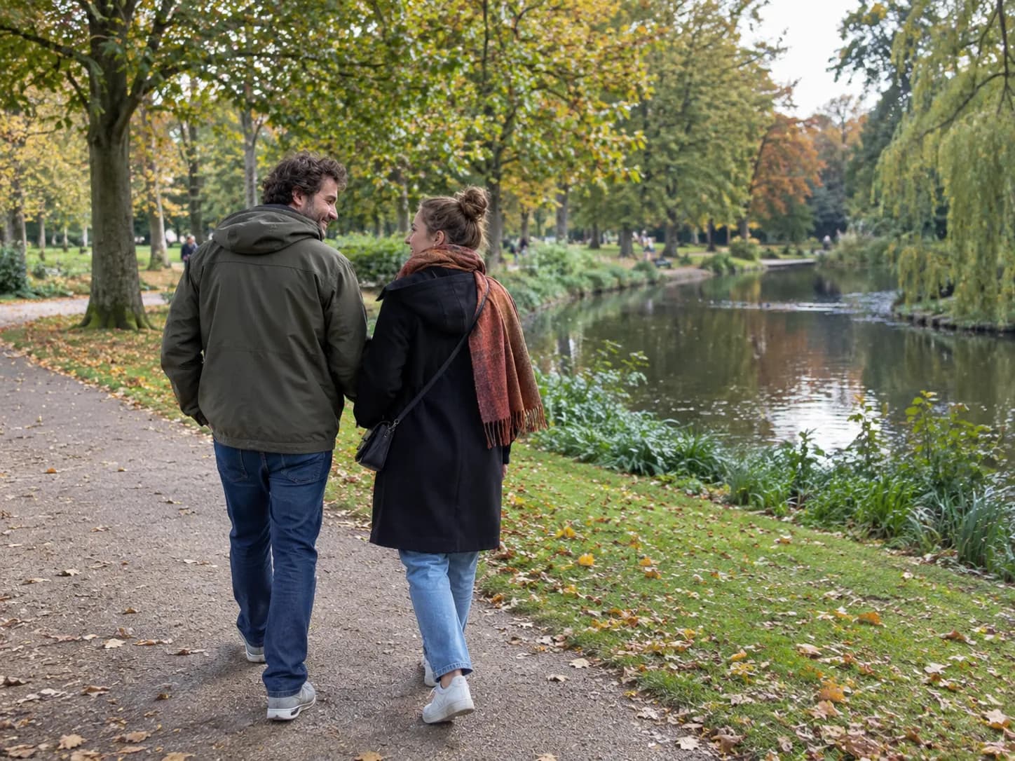 Illustratief sfeerbeeld: twee volwassenen wandelen samen over een stadsparkpad langs bomen en een vijver